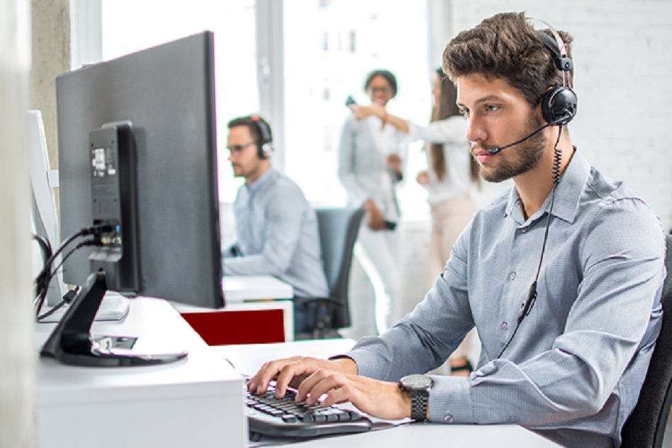 Young handsome male customer support phone operator with headset working in call center.